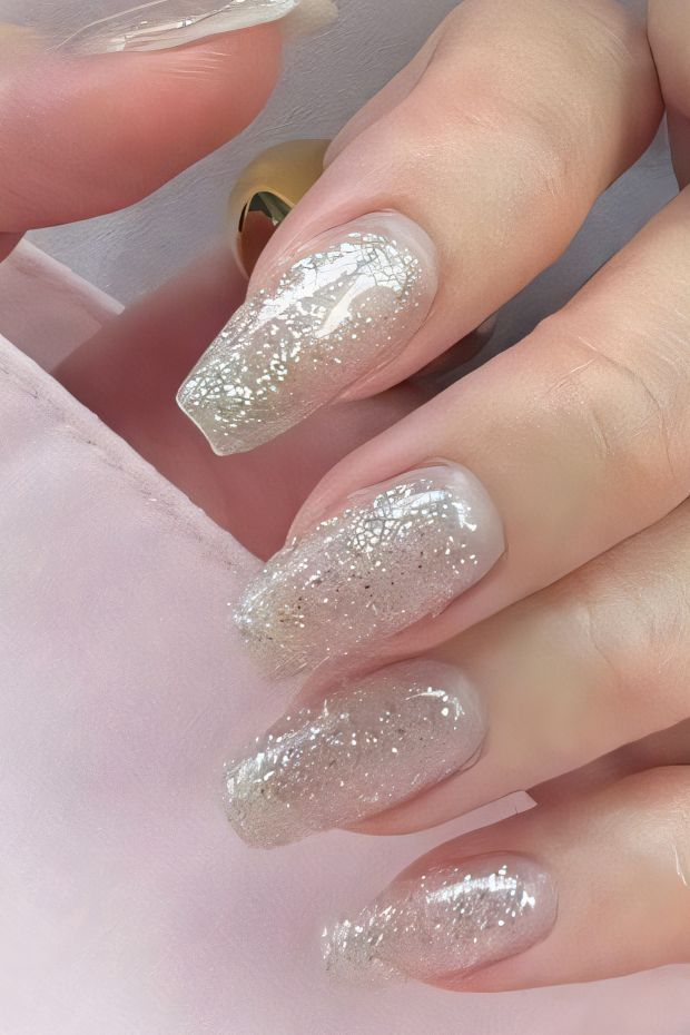 Nail design featuring ombre effect with nude and silver glitter, perfect for elegant and chic nail art.
