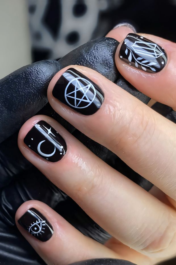 Short black nails with unique white geometric symbols for a trendy and modern nail art design.