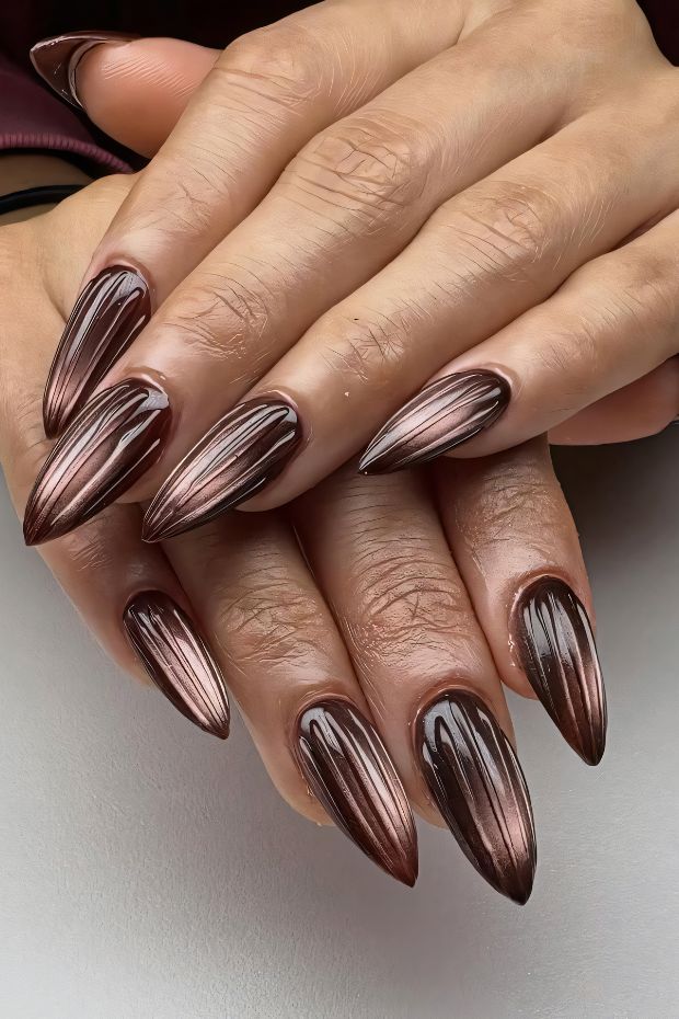 Elegant stiletto nails in a rich brown metallic color with grooved detailing, perfect for a sophisticated look.