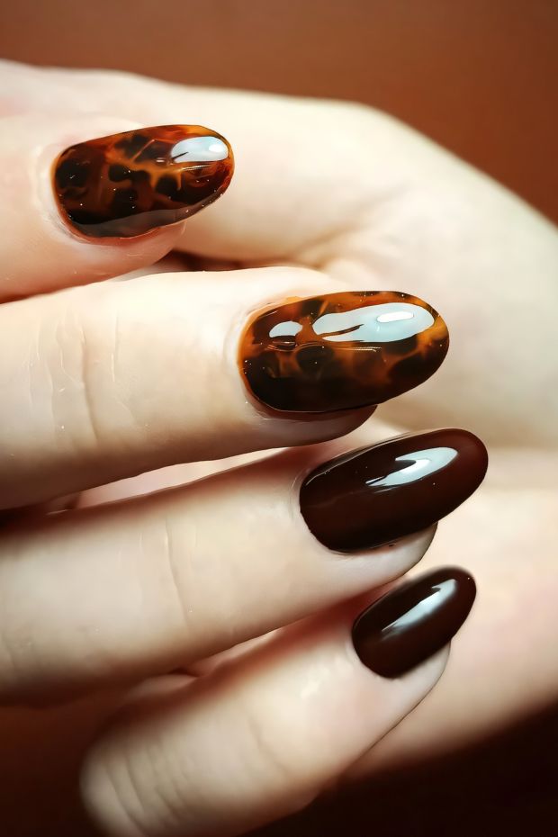 Stylish brown nail design featuring glossy and patterned finishes for a trendy look.