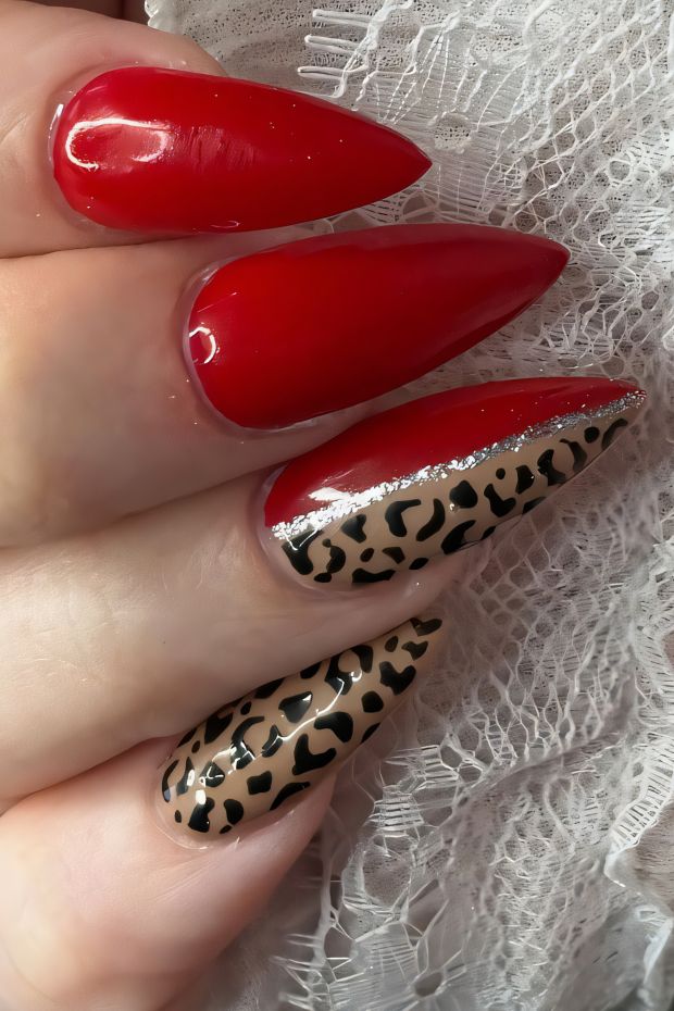 Vibrant red stiletto nails with beige leopard print accent and gold detailing for a chic nail design.