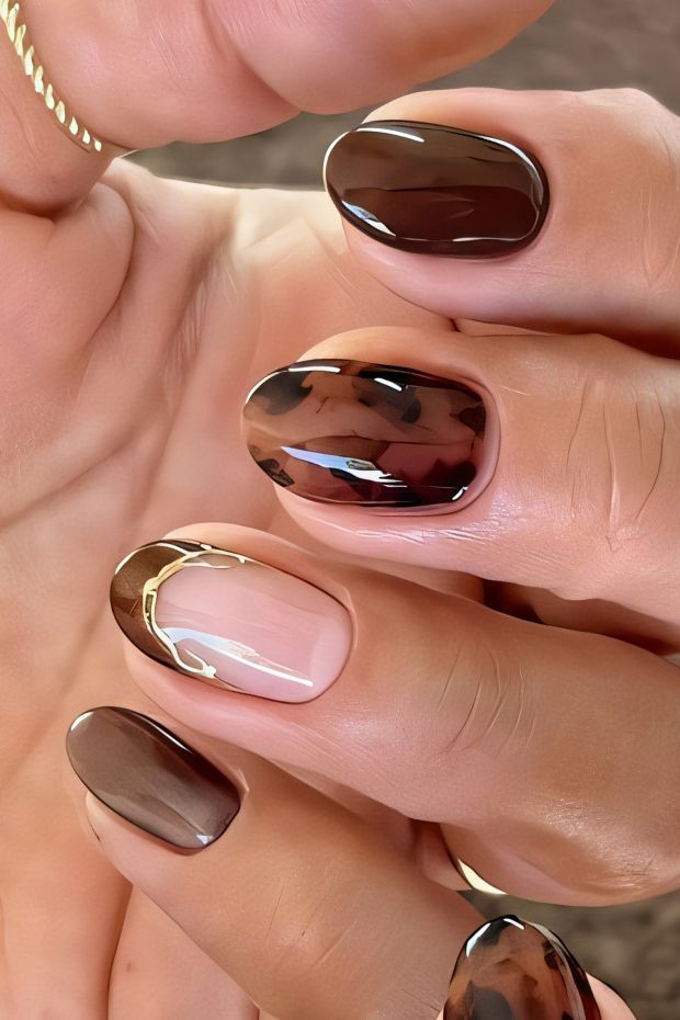 Chic brown nails featuring unique designs and gold accents for a stylish manicure look.