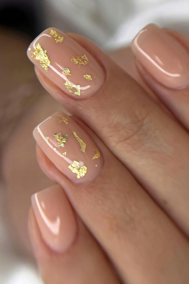 Nude nail design with gold foil accents creating a chic and sophisticated look.