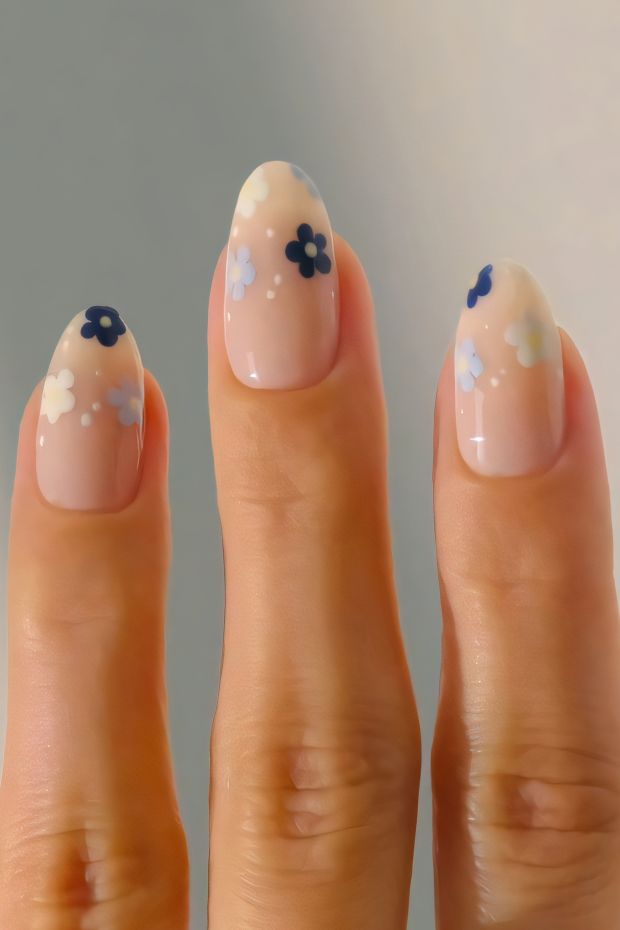 Nude nails with pastel floral designs, featuring blue flowers for a soft and elegant look.