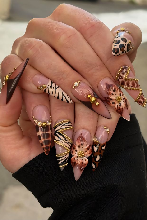 Stiletto nails featuring animal prints, floral designs, and gold accents for a chic and trendy nail art style.