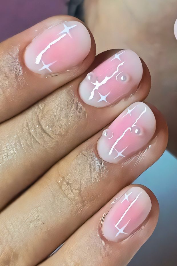Elegant birthday nail design with soft pink base, white accents, and sparkling gems for a stylish celebration.