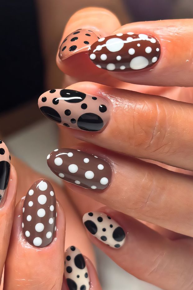 Chic brown nails with black and white polka dots adding a stylish flair to the manicure.