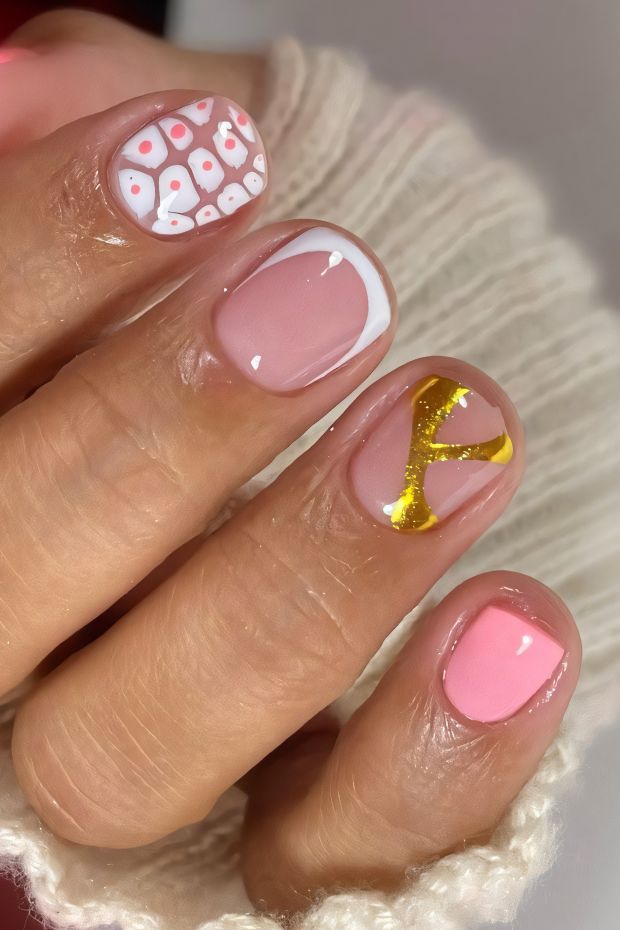 Chic short nail design featuring pink base, white tip, golden accents, and playful patterns for stylish nail art.