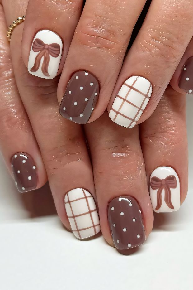 Chic brown nail design featuring white polka dots, grid patterns, and bows for an elegant touch.