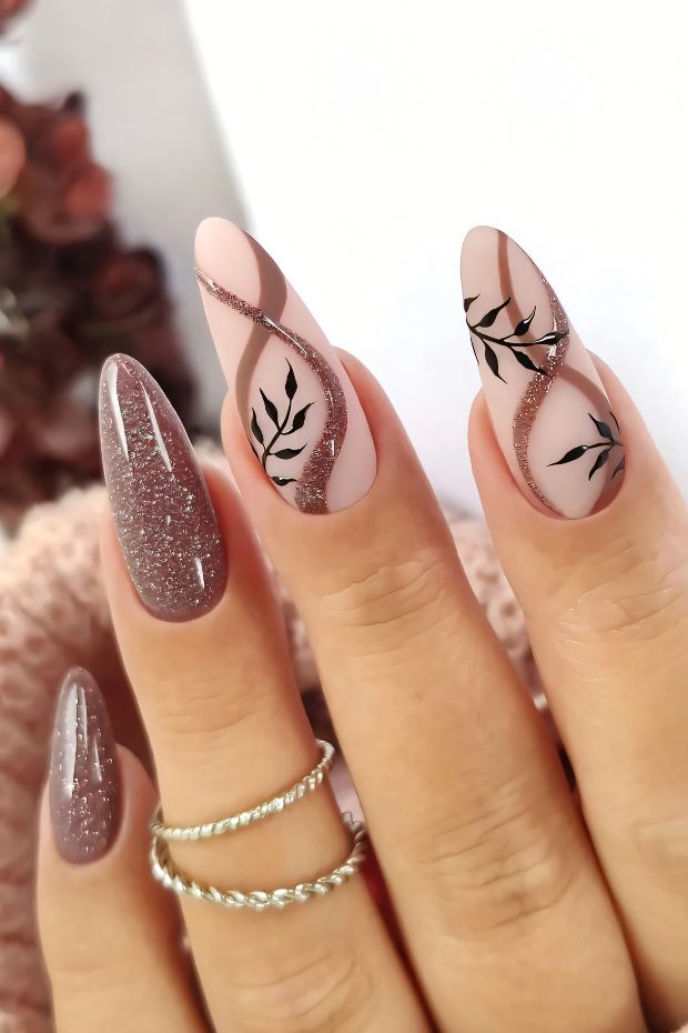 Beautiful brown nails with elegant leaf designs and glittery accents, showcasing modern nail art trends.
