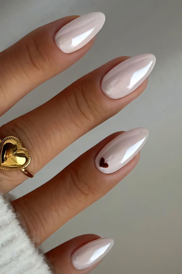 Glossy light pink almond nails with a heart accent design, ideal for elegant and romantic looks.