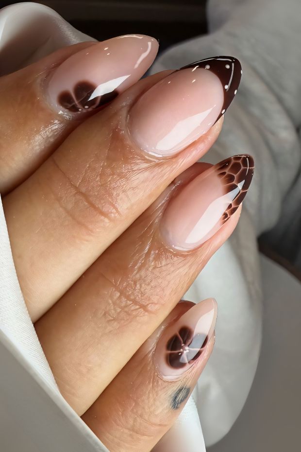 Chic almond-shaped nails with a brown ombre design and delicate floral accents for a sophisticated nail art look.