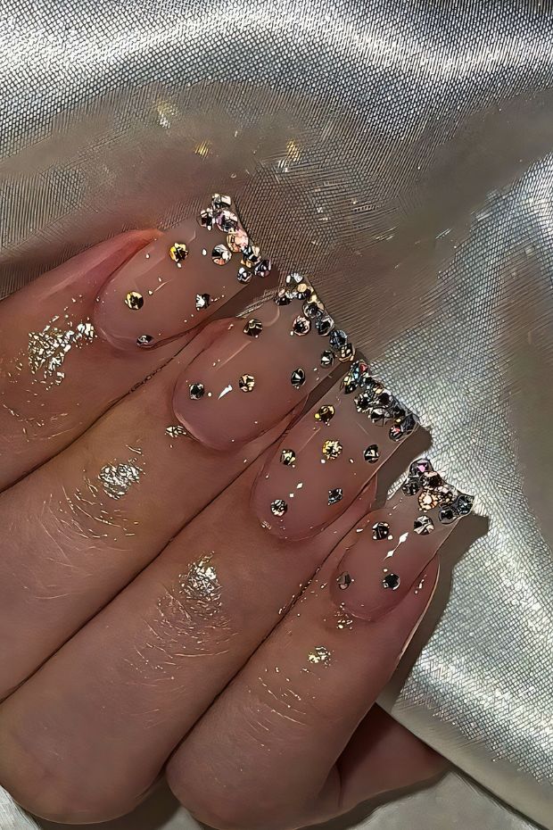 Glamorous birthday nails with nude base and sparkling rhinestones, featuring exquisite glitter accents for a festive look.