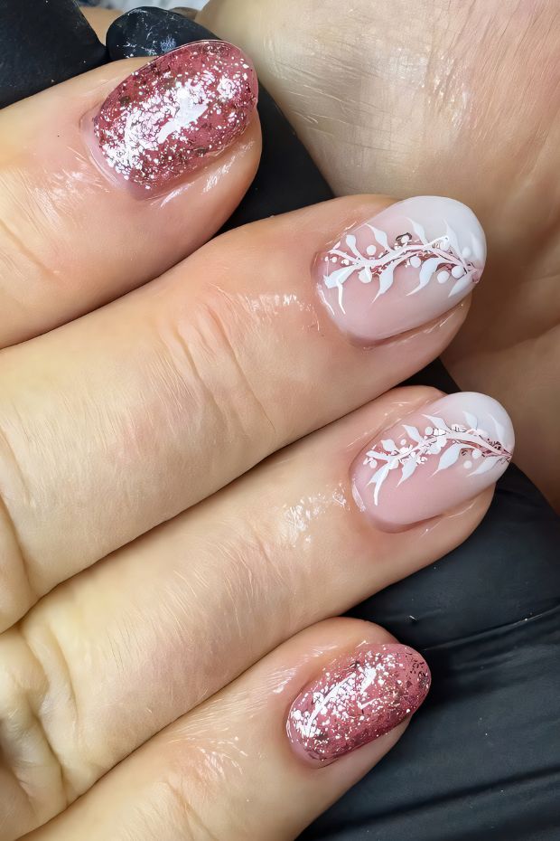 Birthday nails featuring glittery rose-gold, nude base, and elegant white floral designs for a festive look.