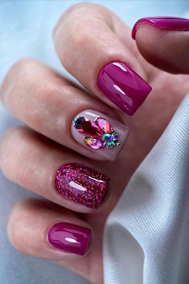 Short nails featuring vibrant pink polish with floral designs and glitter accents, showcasing a playful and chic nail art style.