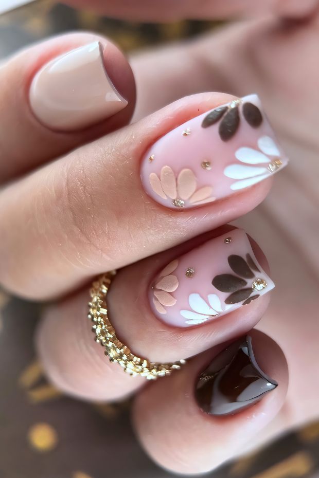 Chic brown nail design with floral accents and glossy finishes, featuring unique details and sparkling embellishments.
