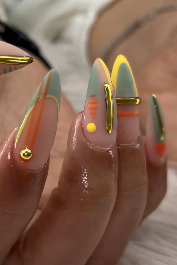 Stylish stiletto nails with pastel colors, geometric designs, and gold accents for a trendy look.