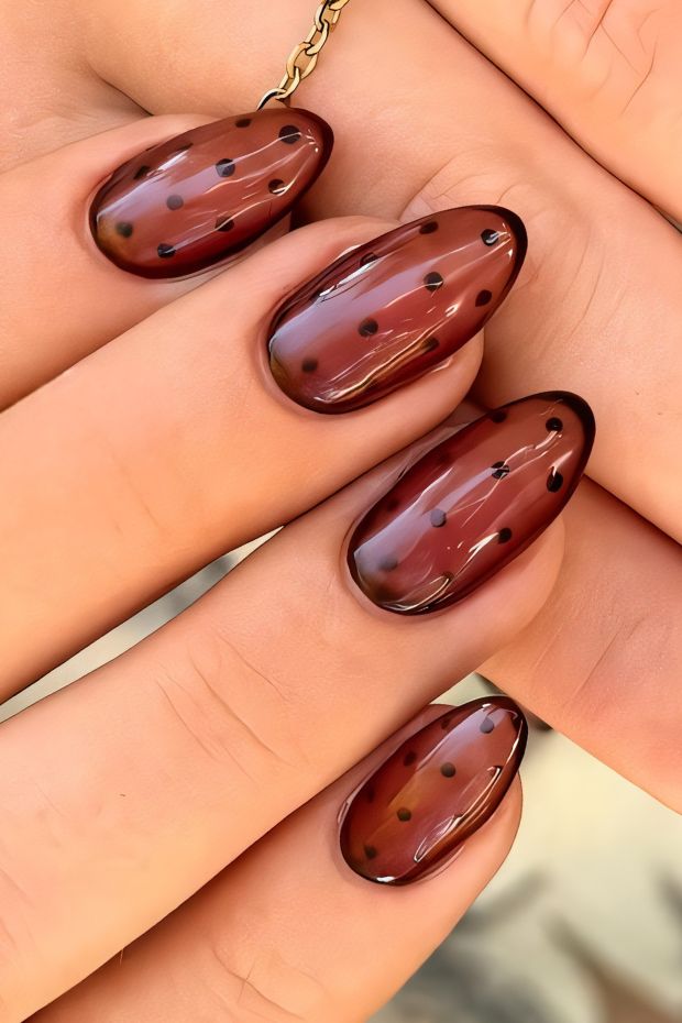 Dark brown nails with glossy finish and black dotted design for a trendy, sophisticated look.