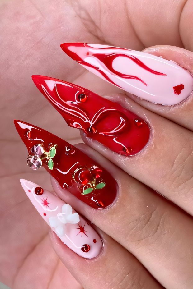 Bold stiletto nails in red and pink with flame design and decorative embellishments, perfect for a trendy look.