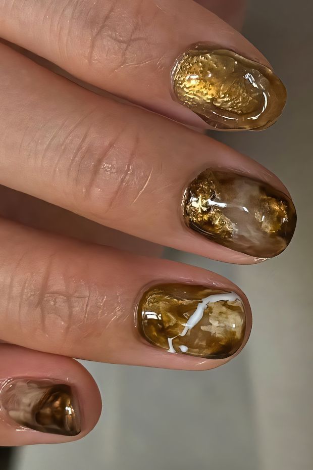 Brown marble nail art with gold accents and glossy finish, showcasing natural elegance and style.