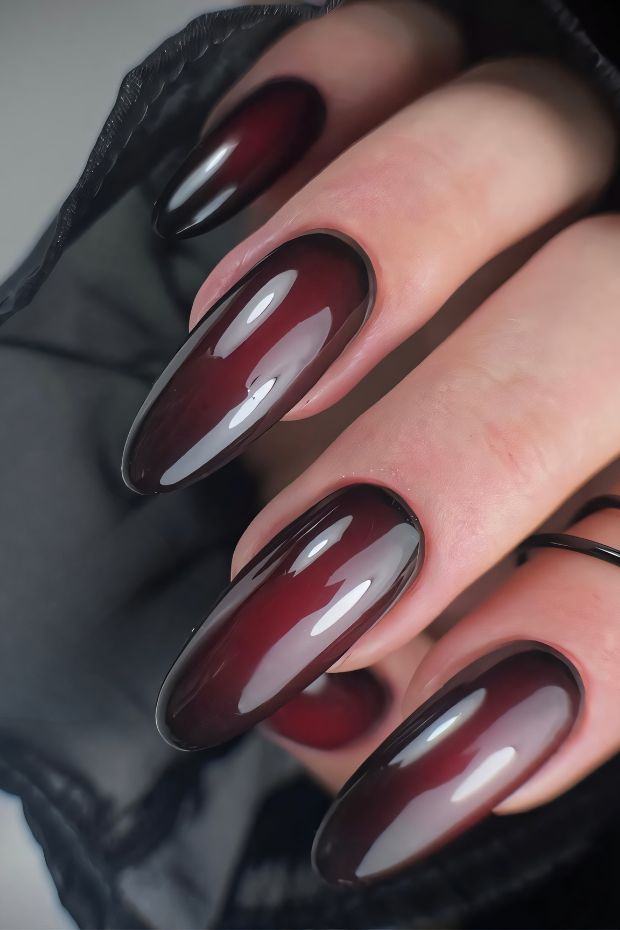 Elegant deep red ombre nail art with glossy finish on almond-shaped nails for a stunning look.