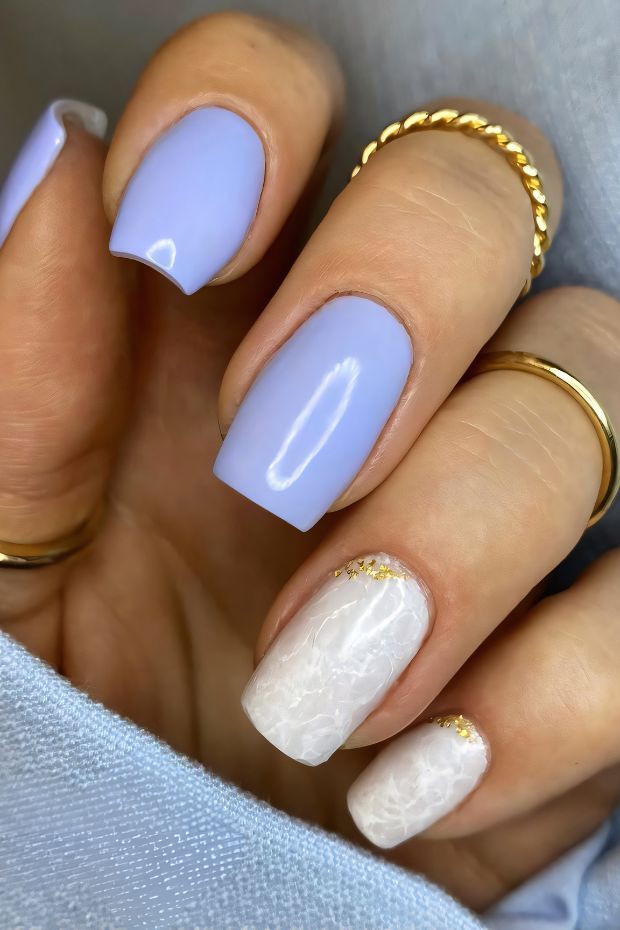 Chic short lavender nails with marble accents and gold details for a modern and elegant look.