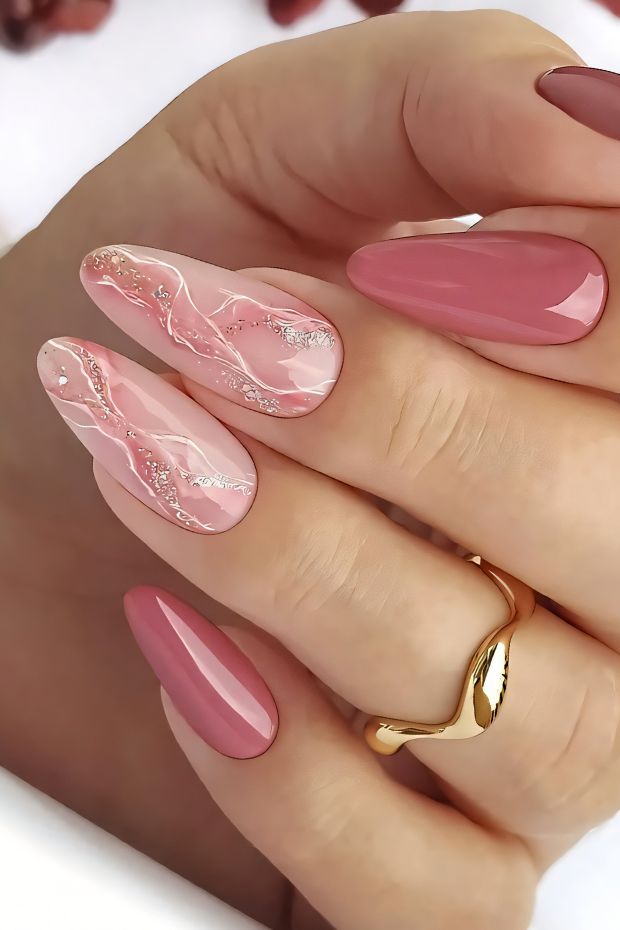 Elegant pink marble nail design with subtle glitter accents on a hand holding rings.