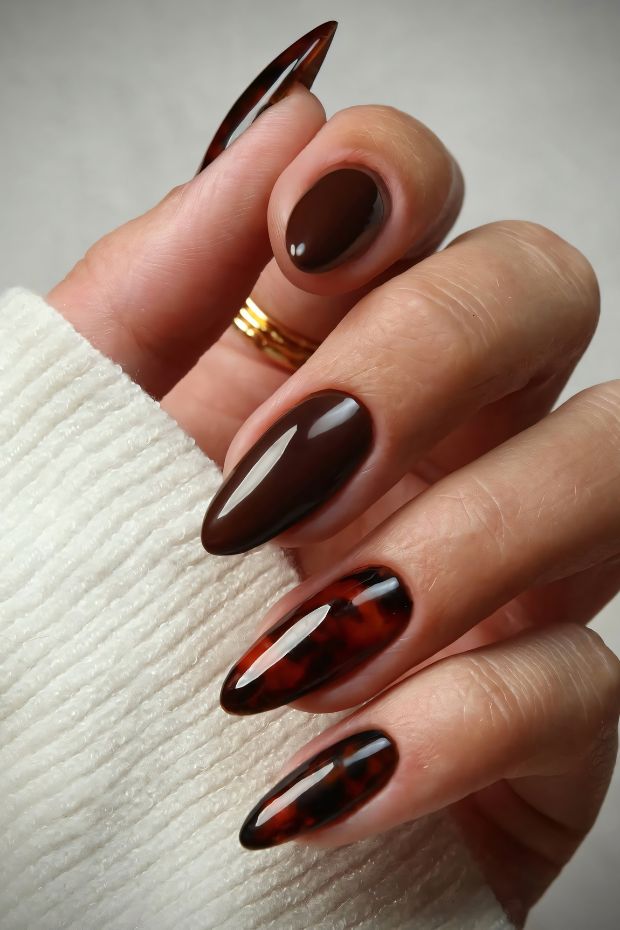 Stylish brown almond-shaped nails with glossy finish and tortoiseshell accents for a trendy look.