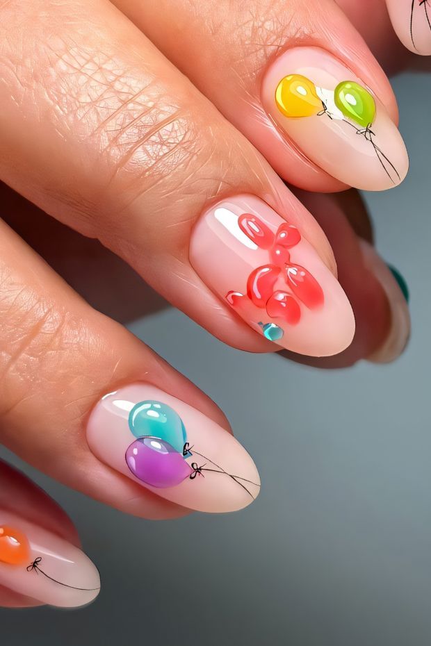 Colorful birthday nail art featuring balloons in vibrant shades like green, yellow, blue, and pink on a nude base.