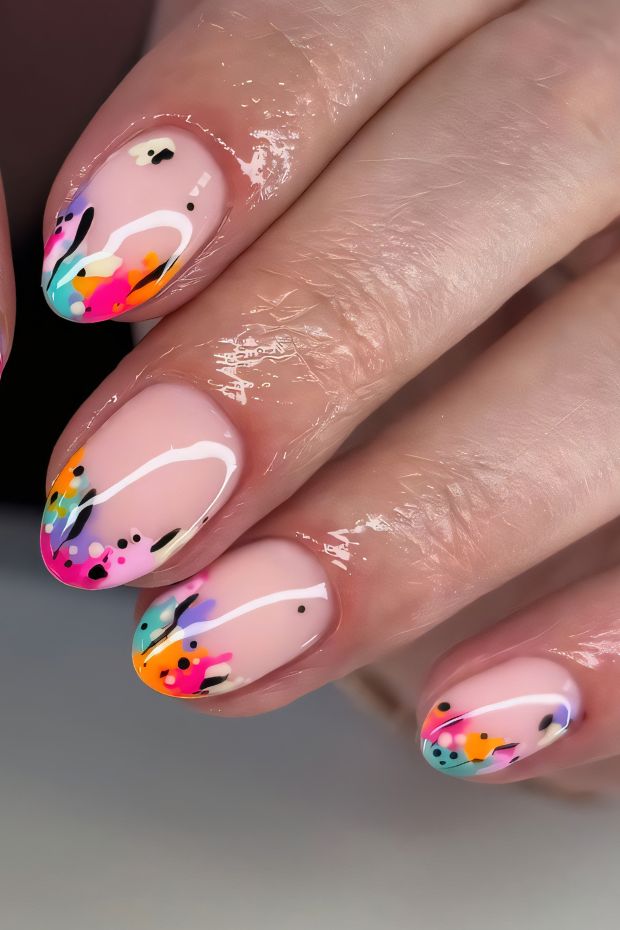Short nails with a pink base and vibrant, colorful patterns featuring black, orange, blue, and green accents.