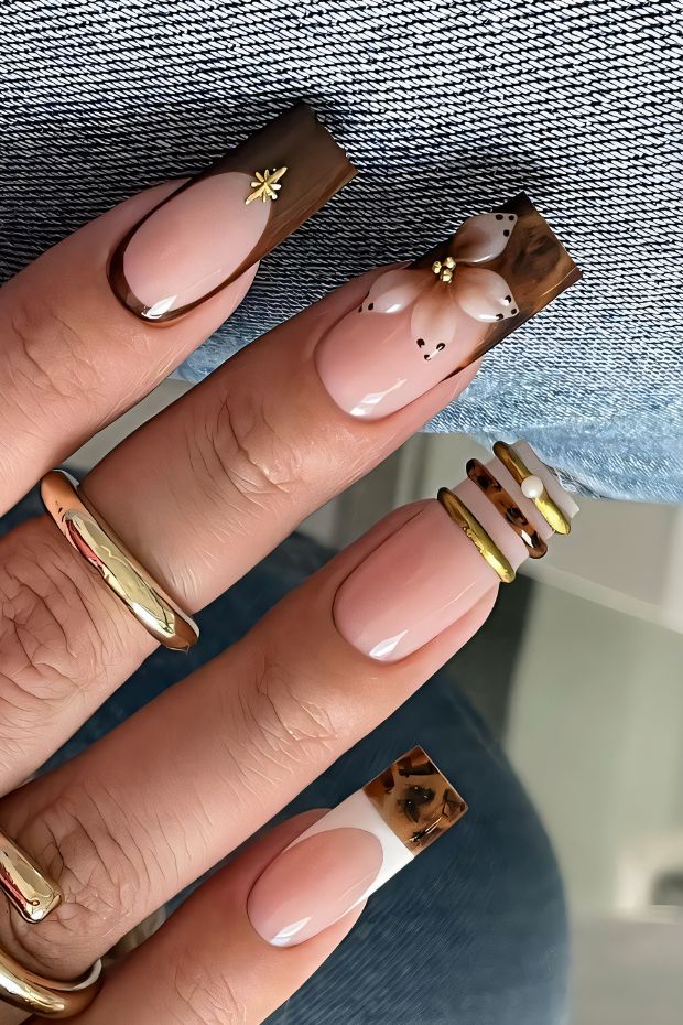 Stylish brown and nude nail design with floral accents and gold details, perfect for a chic manicure.