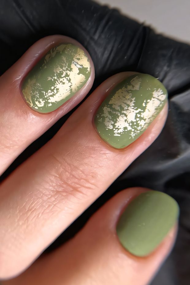 Matte olive green nails with gold flakes for a trendy and elegant nail art design.