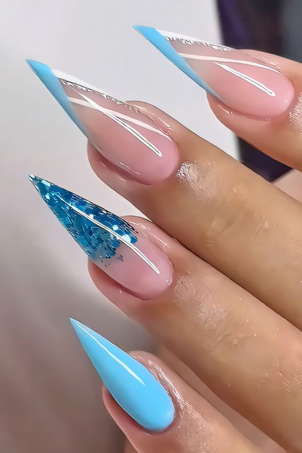 Trendy stiletto nails featuring blue accents and metallic details with a glossy finish.