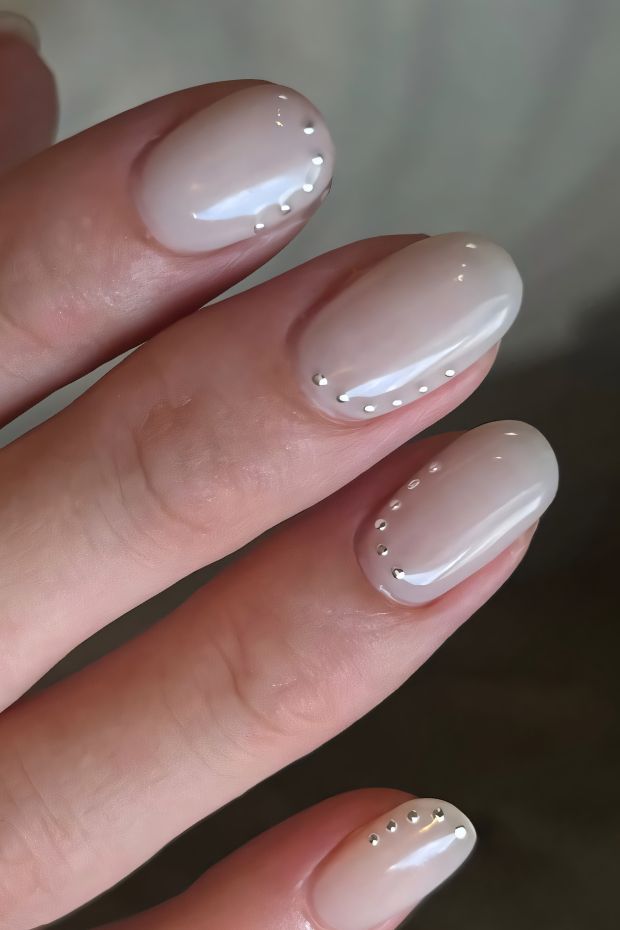 Nude nails with metallic studs for a chic and elegant look, perfect for versatile styles.