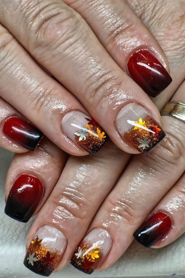 Ombre red and black nail design adorned with glitter and gold star embellishments for a unique, striking look.