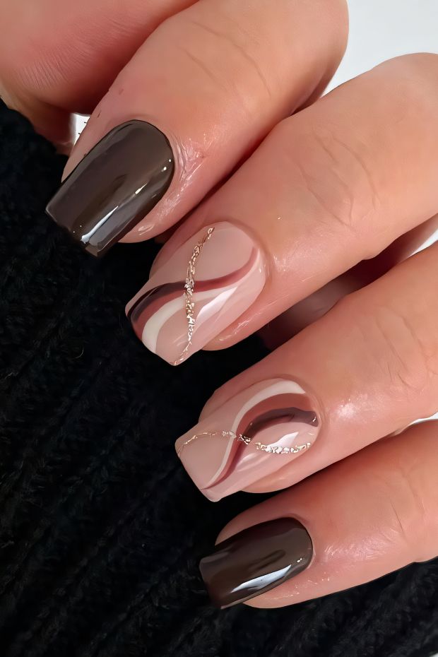 Elegant brown nail art with swirling designs and gold accents, perfect for a chic look.