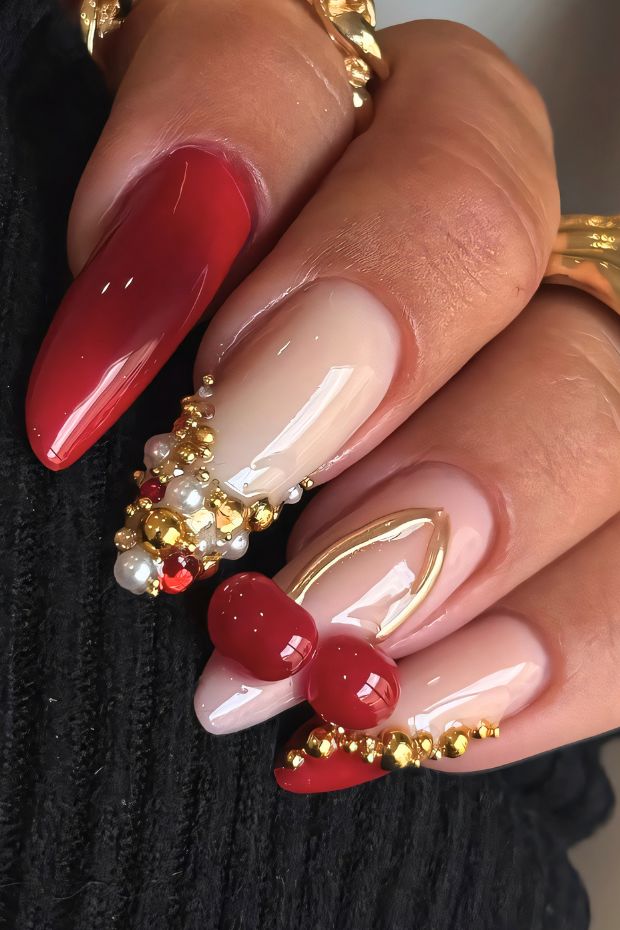 Glamorous red nail design featuring gold accents and detailed embellishments for a chic aesthetic.