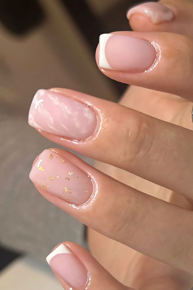 Elegant pink nail design featuring gold accents and French tips for a chic, modern look.
