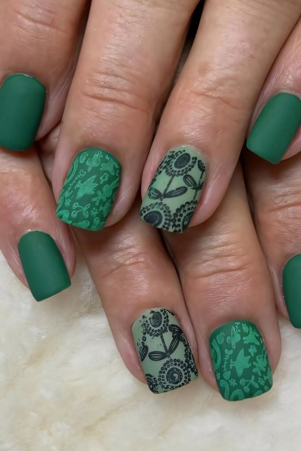 Matte green nail design with intricate black patterns, showcasing a blend of creativity and elegance for stylish manicures.