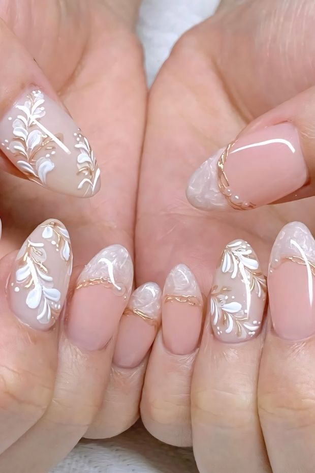 32 Creative Acrylic Nail Ideas You’ll Want to Try This Season 14 Nail art with floral designs in white and gold on a nude base, ideal for elegant acrylic nail inspiration.
