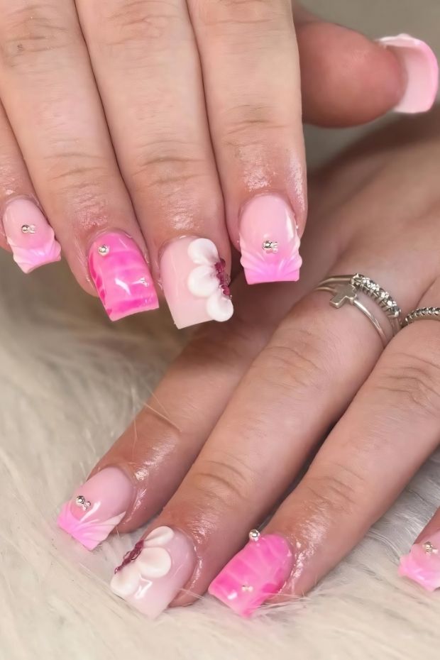 32 Creative Acrylic Nail Ideas You’ll Want to Try This Season 20 Unique pink acrylic nails with floral accents and gems, showcasing trendy nail art designs.