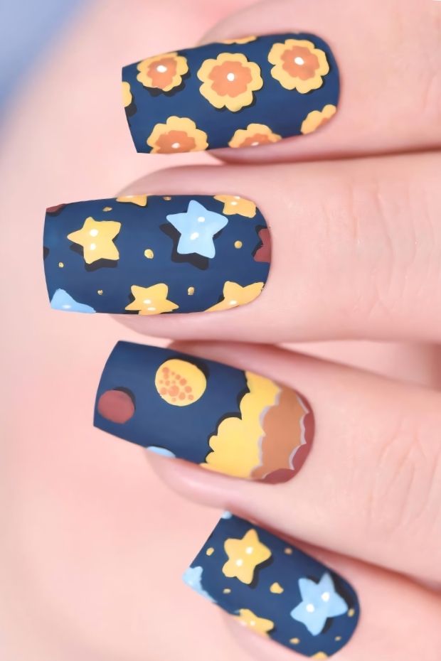 Matte nail design featuring floral patterns and stars on a deep blue background for a creative and chic manicure.