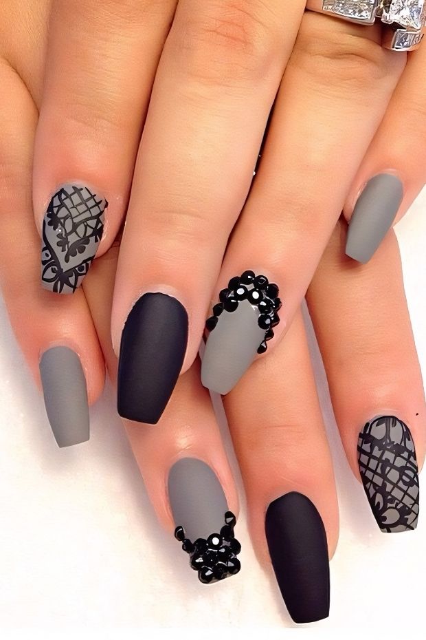 Matte black and grey nail designs with intricate patterns and embellishments for sophisticated nail art.